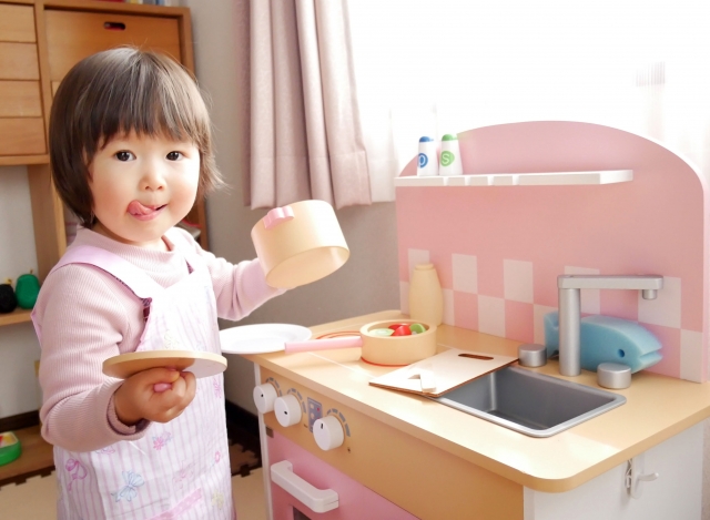 おもちゃのキッチンで、おままごと遊びをする女の子