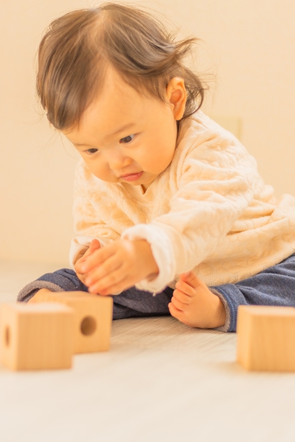 積み木で遊ぶ赤ちゃん。指先を使う遊びはスプーンの練習にもつながる